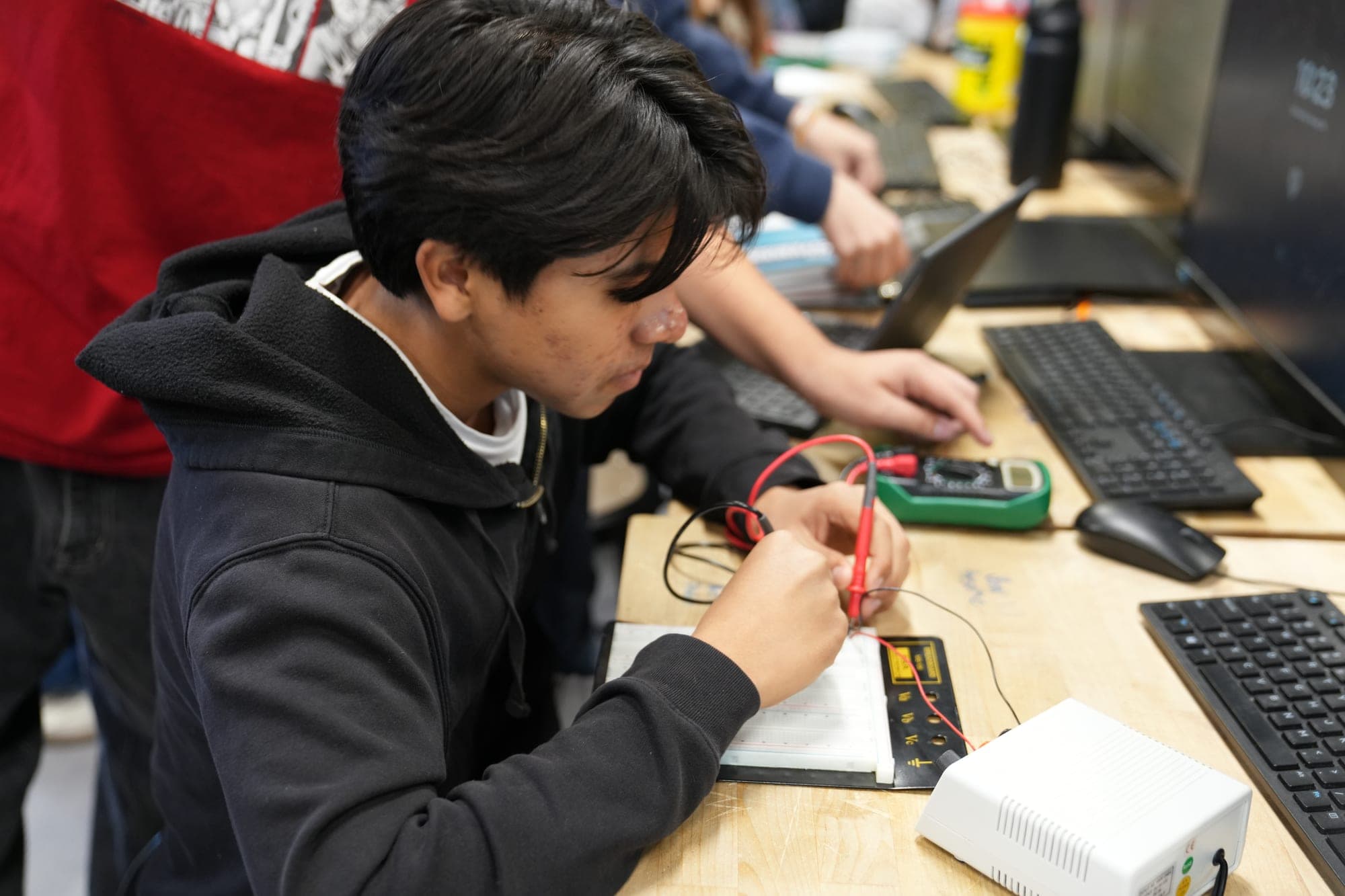 A Highland Prep West student testing a circuit at a classroom workstation